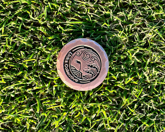 a birds eye view of a forged iron luxury golf gift ball marker on a perfect fescue grass golf course