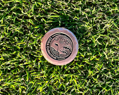 a birds eye view of a forged iron luxury golf gift ball marker on a perfect fescue grass golf course