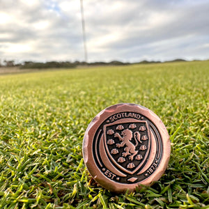 Official Scotland team merchandise - golf ball marker on a pristine golf green with the sun setting