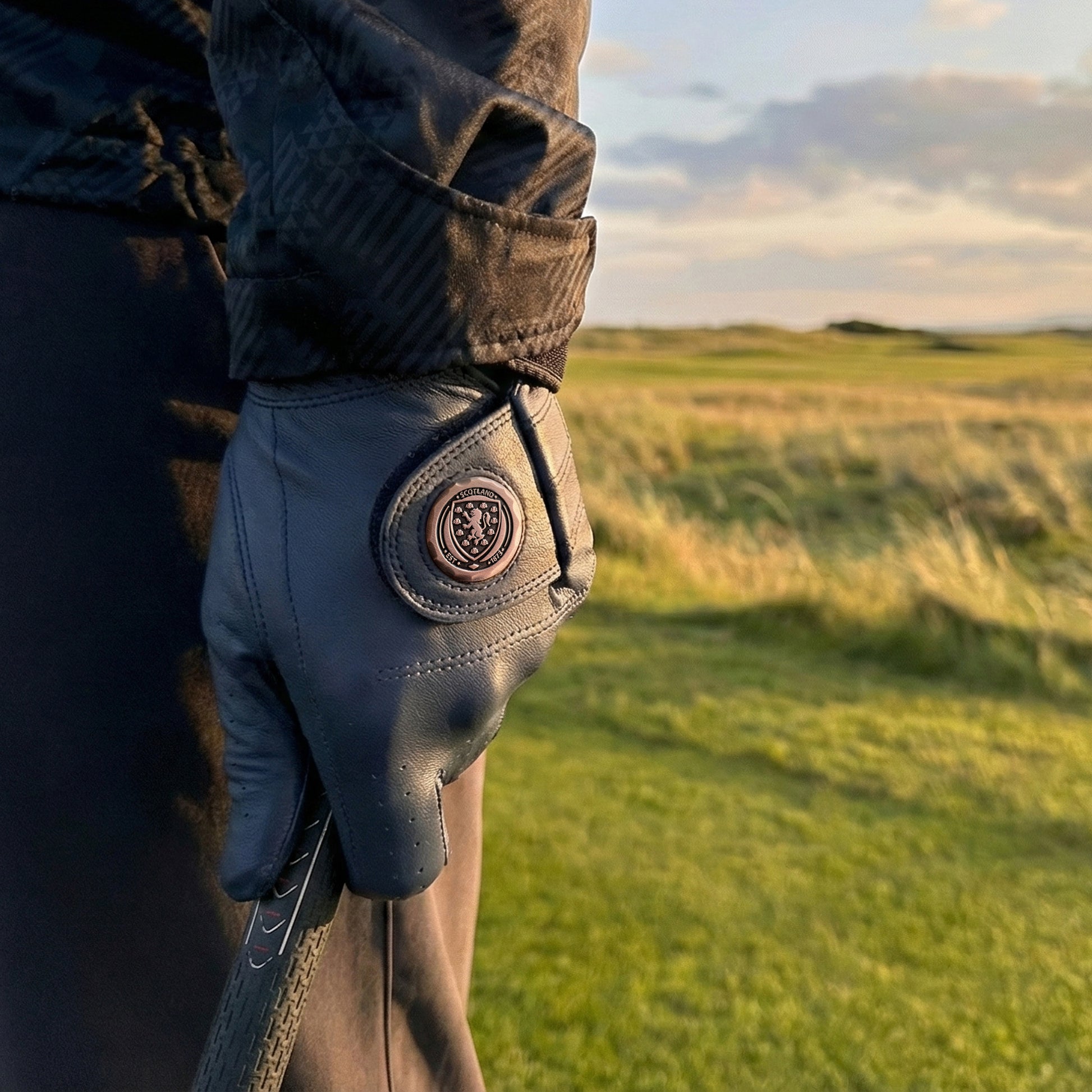 Premium Navy leather golf glove on stunning links golf course with fescue grass and dunes.