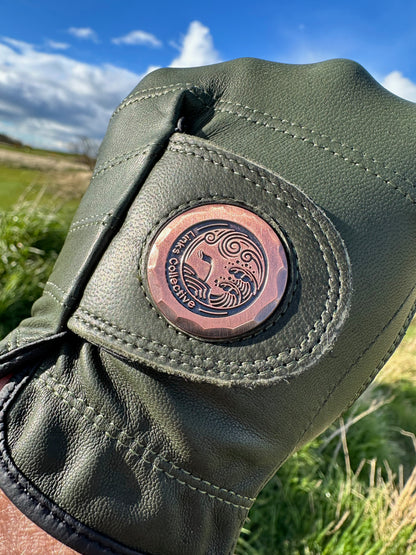 Detail view of the ergonomic strap design and logo on green golf Glove by Links Collective. playing on a Scottish golf course.